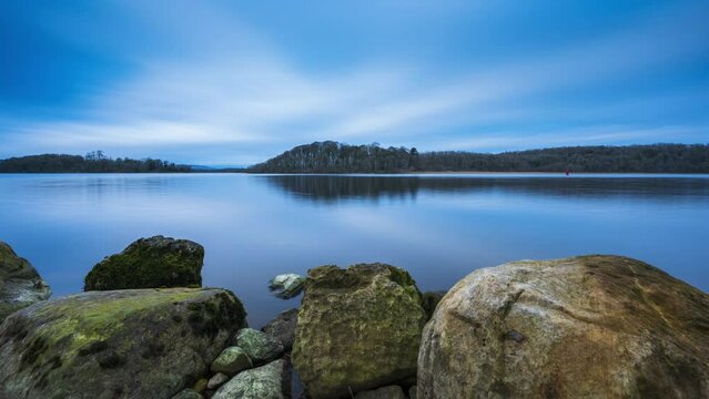 Time lapse of a rocky shore foreground with forest in distance on a cloudy sunny day at Lough Key in county Roscommon in Ireland.
