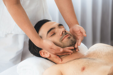 Caucasian man enjoying relaxing anti-stress head massage and pampering facial beauty skin recreation leisure in dayspa modern light ambient at luxury resort or hotel spa salon. Quiescent - obrazy, fototapety, plakaty