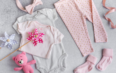Set of baby bodysuits, pants, socks and knitted toy on grey background. - 791324817
