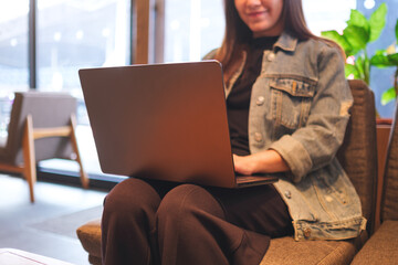 Closeup image of a young woman using and working on laptop computer in cafe