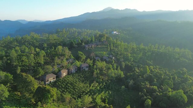 Aerial drone landscape of morning sunrise over housing on farmland in nature forest with mountains in background Little Adam's peak Ella Sri Lanka Asia