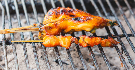 Chicken is fried on wooden skewers over coals