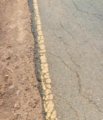 Yellow line along the edge of an old asphalt road