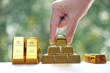 Woman hand hold the gold bar on natural green background, investment and business concept