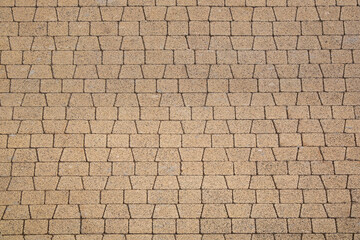 The surface is made of sand-colored paving slabs of trapezoidal and rectangular shape.