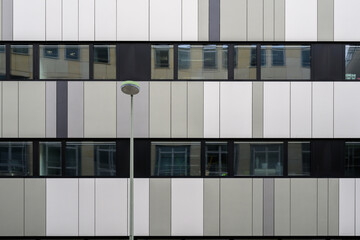 A grey office facade with a street lamp in the foreground - 791334622