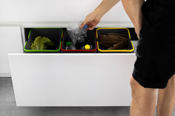 A young man sorts garbage in containers in the kitchen in slow motion. Modern kitchen with a system...