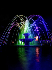 Beautiful fountain in city park with colorful light effects at night.