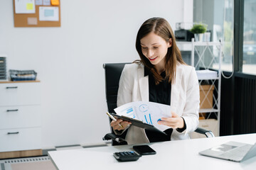 Young woman using laptop and tablet while sitting at her working place. Concentrated at work..