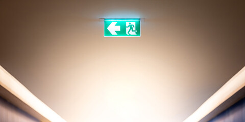 Green emergency exit sign or fire exit sign showing the way to escape with arrow symbol. - 791347293