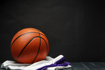 Vibrant Orange Basketball Resting on a Dark Wooden Floor With White and Purple uniform