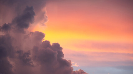 Sunset sky clouds at dusk with pink, yellow and purple sunlight after sundown or golden hour....