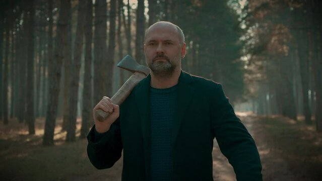 Man Holding Large Axe in Forest, mentally ill serial killer walking through woods. Bloodthirsty criminal maniac carrying case, searching for victim