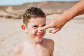 Boy with sunscreen lotion on face. Young boy si protected from sun with sunscreen. Concept of beach...