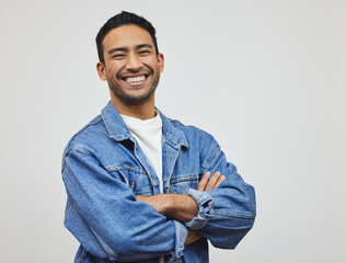 Happy, man and portrait with arms crossed, fashion and modern style in a studio with smile. Trendy, denim and cool outfit with confidence and classic casual clothes with jacket and grey background