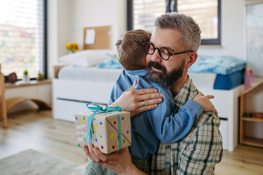 Dad get a handmade gift from little son, present wrapped in diy homemade wrapping paper. Happy Fathers day concept.