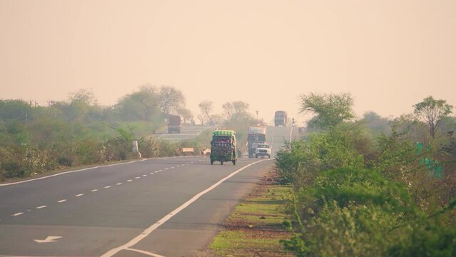 A tempo rikshaw and cars moving on a national hjghway motor road in Central India