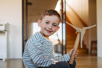 Boy holding wind turbine model. Concpet of renewable energy sustainable lifestyle for next generations.