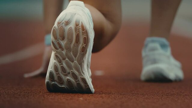Track runner taking off in extreme slow motion, runner sprint start shoes macro close up in 4k 800fps, one foot forward