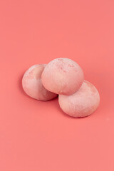 Traditional Japanese dessert, mochi cake in thin pink rice dough on a pink background, open space
