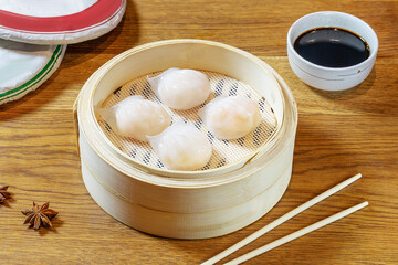 Chinese dim sum dumplings with shrimp in a wooden bowl.