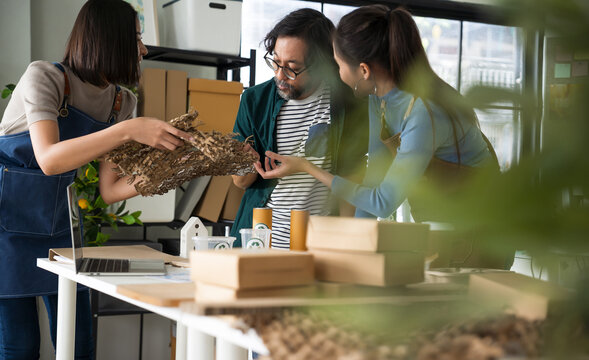 Asian business meeting features a female entrepreneur in apron showcasing eco-friendly, reusable product. The discussion centers on environmental protection and building a sustainable business model