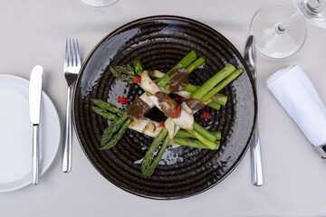 Rolled asparagus with truffle,  cheese and caviar served on a black plate - 791378036