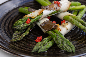 Rolled asparagus with truffle,  cheese and caviar served on a black plate - 791378047