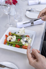 Hands eating caprese salad with asparagus - 791378814