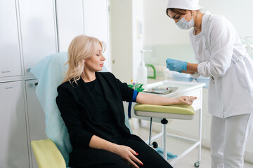 Professional female nurse preparing test collection for lady patient. Woman waiting medical...