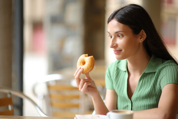 Amazed woman eating delicious doughnut in a bar - 791380671