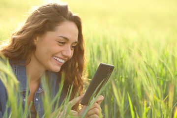 Happy woman in a field using cell phone