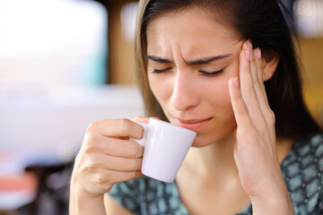 Worried woman drinking coffee suffering head ache