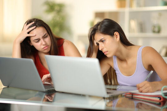 Two frustrated students complaining checking laptop