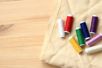 Spools of thread of different colors, top view. Set of various colorful sewing threads on fabric, close-up. Sewing