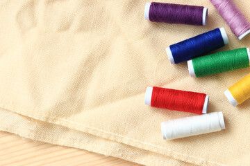 Spools of thread of different colors, top view. Set of various colorful sewing threads on fabric,...