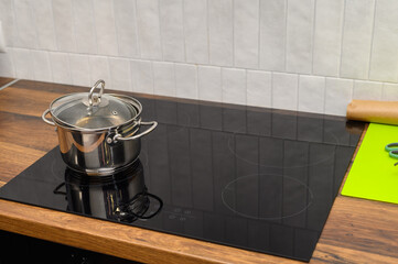 Garnek stoi na czarnej płycie grzewczej elektrycznej w nowoczesnej kuchni