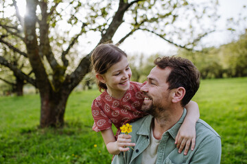 Father looking at his daughter lovingly in spring nature. Father's day concept.