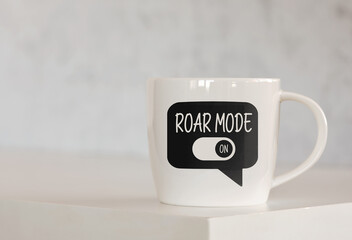 The message roar mode on a speech bubble printed on a coffee mug over the table.