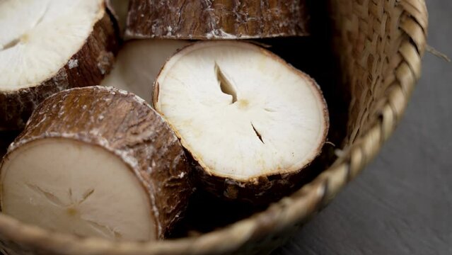 Raw yucca (cassava root) slices on a eco bowl on a brown board. Manioc farm harvest. Healthy ingredient. Rotation