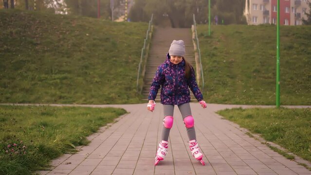 Eight years girl roller skating in slow motion outdoors in city park at autumn cloudy day. Training hobby active leisure lifestyle children spending free time