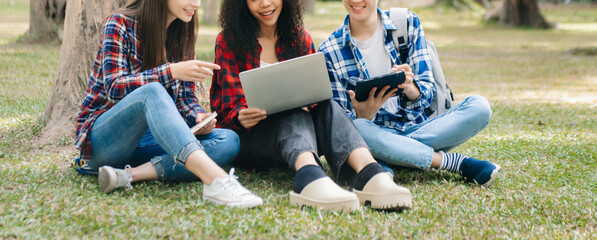 Three young Asian college students and a female student group work at the campus park in morning