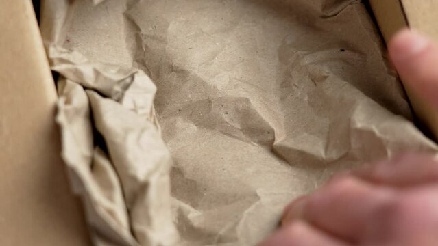 Preparing a parcel cardboard box filling with crumpled brown paper. Empty shipping container