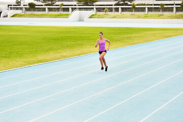 Fototapeta premium Fitness, sports woman and running on race track for athletics, sprint challenge or competition training in stadium. Runner, exercise and female person for performance, endurance or cardio workout