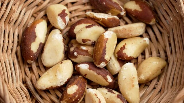 Organic dried Brazil nuts in rustic rattan bowl close up. Tasty nutty snack. Nutritional source of selenium nutrient. Top view. Rotation