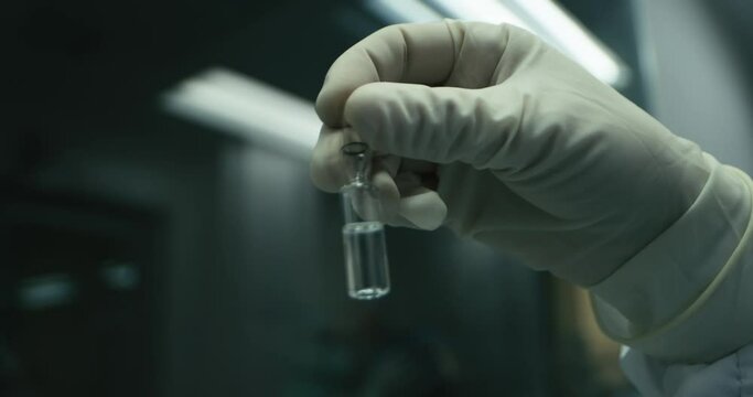 A surgeon holding an ampule with hand wearing gloves.