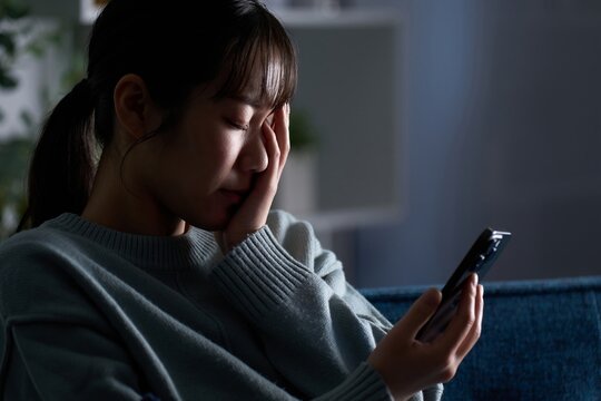スマートフォンを見て落ち込む女性