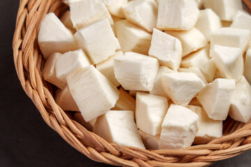 Chopped cassava (yucca) sliced root in rustic rattan bowl on a wooden table