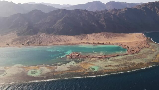 Aerial view captures the stunning blue lagoon in Dahab, Egypt, offering breathtaking scenery of the surrounding desert landscape, guaranteeing visitors an unmatched and unforgettable experience.