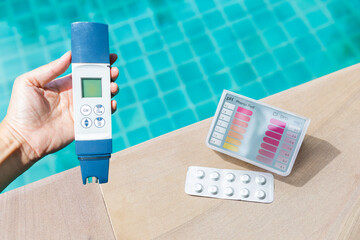 Pool tester test kit and digital water tester on swimming pool edge, summer outdoor day light, water quality testing, quality tester for healthy swimming pool water